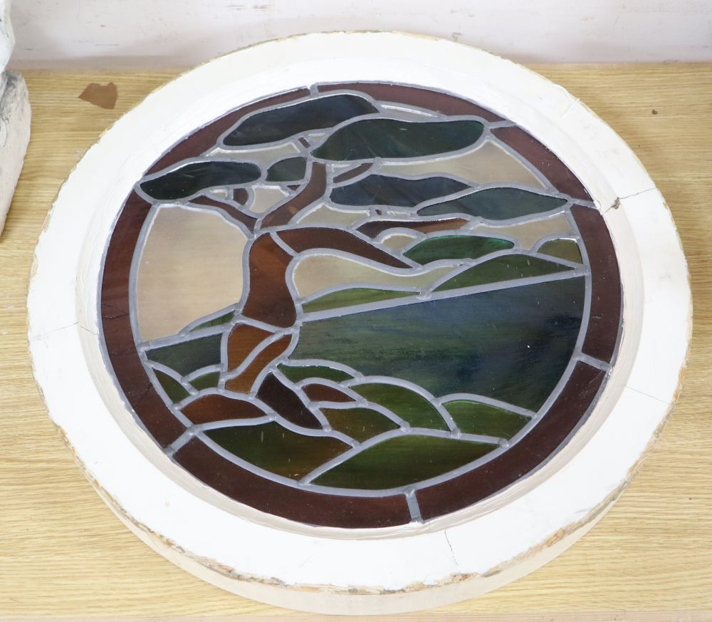 An Art Deco circular stained glass panel depicting a tree, housed in a painted wood frame, overall diameter 60cm